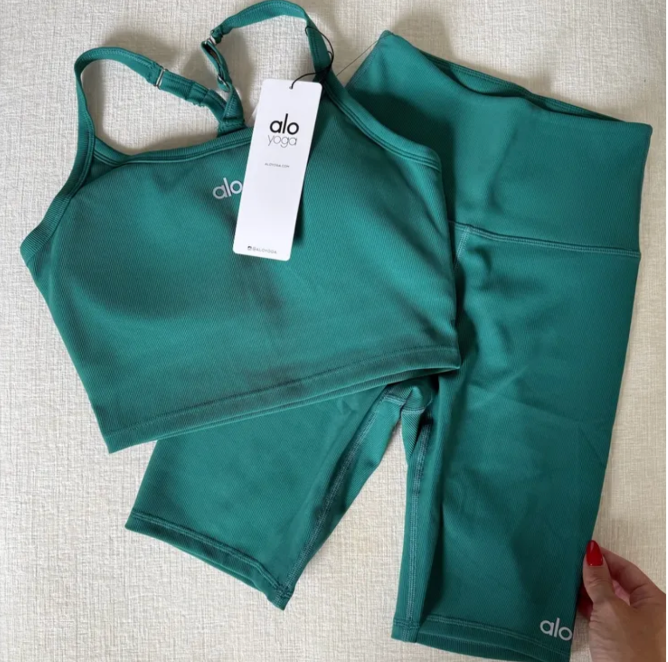 Teal athletic top and shorts set with 'alo' branding on a textured surface.