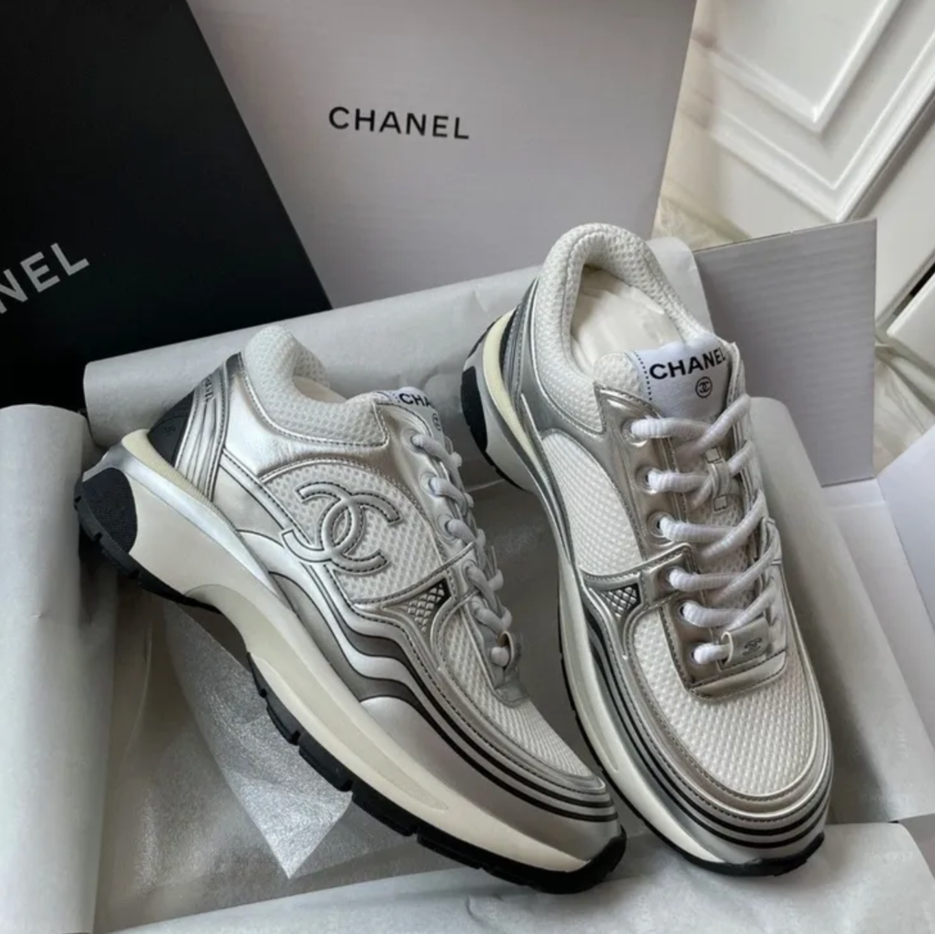 White Chanel sneakers with black accents in a box